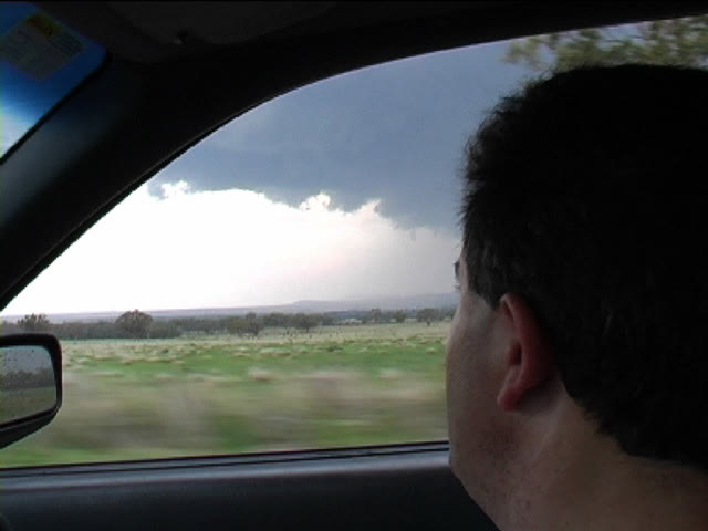 A chaser looking out of the vehicle window at a developing storm