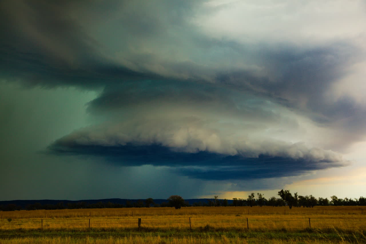 A green-tinged supercell over golden paddocks