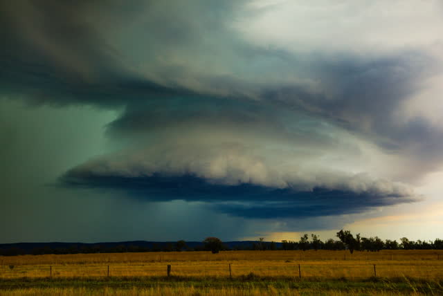 A green-tinged supercell over golden paddocks