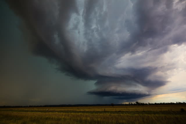 Dark storm base with rain shafts over paddocks